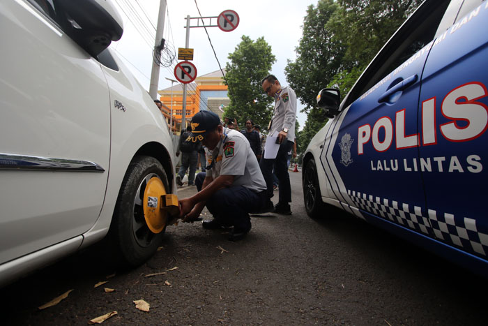 BERHARAP EFEK JERA: Salah satu mobil yang terparkir liar di Jalan Jaksa Agung Suprapto digembok petugas, kemarin (10/6).