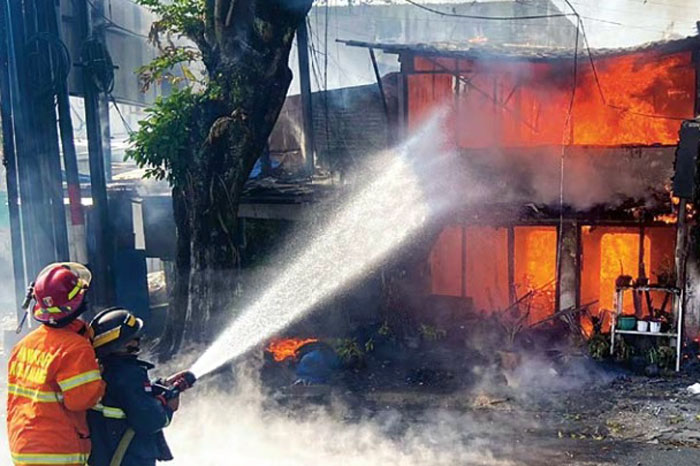 DIDUGA GANGGUAN JIWA: Petugas Damkar Kota Malang berupaya memadamkan api yang melalap bangunan dua tingkat di Jalan Ahmad Yani, Kecamatan Blimbing kemarin.