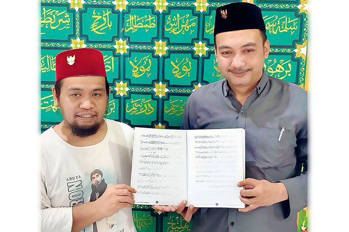 EKSTRAKURIKULER: Pengurus YPP UNIQ Nusantara Ubad Aminullah (kiri) dan salah satu rekannya menunjukkan buku tentang huruf Suryani yang diajarkan kepada para santri.