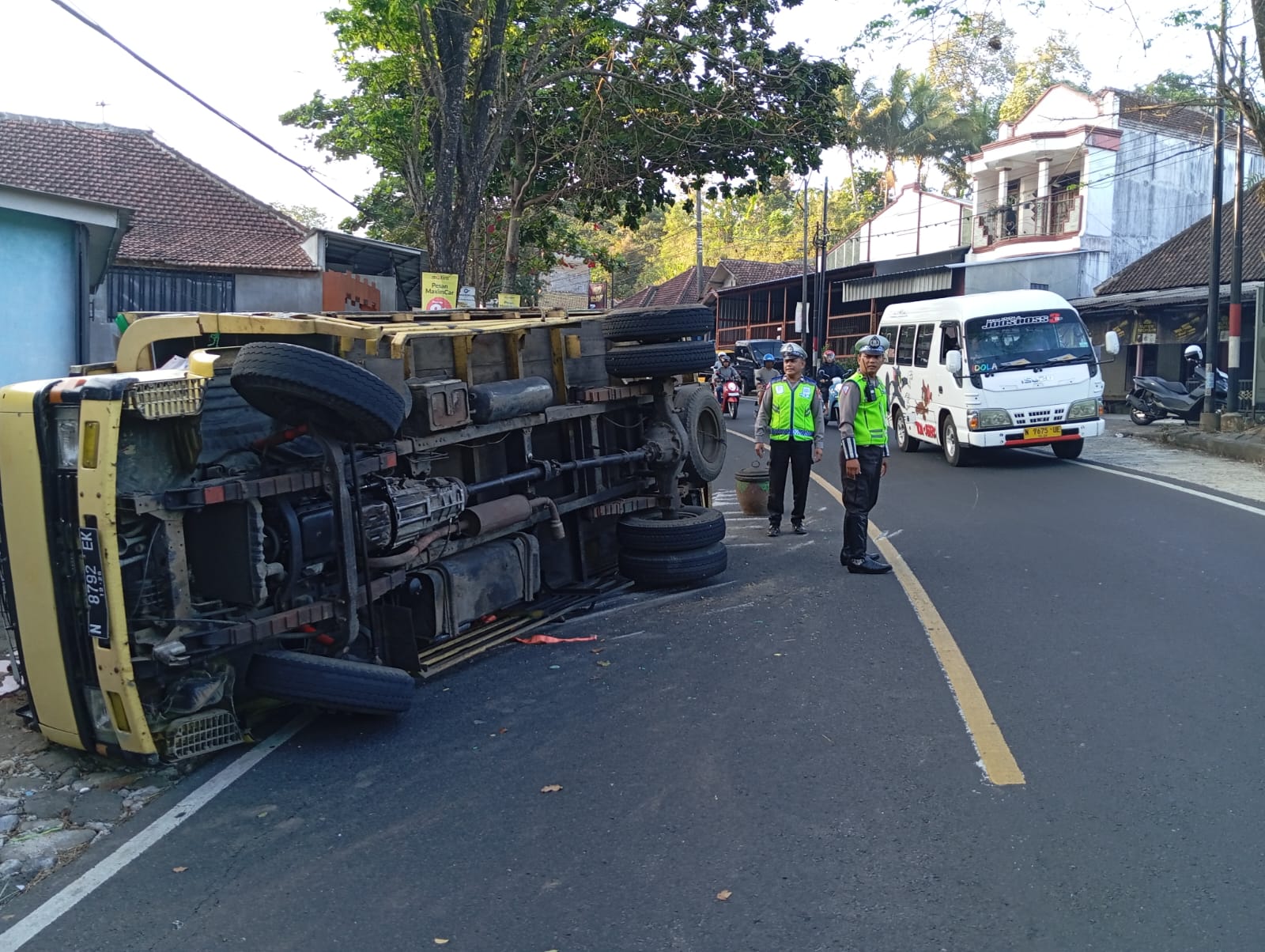 CEGAH MACET: Dua personel dari Polres Malang berjaga di lokasi kecelakaan sambil mengatur arus lalu lintas. Laju kendaraan sempat terhambat karena bak truk menutup sebagian ruas jalan.