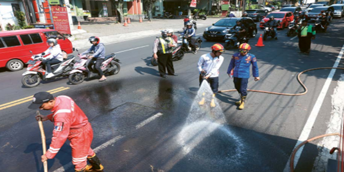 MAKIN SERING: Petugas Damkar Kota Malang membersihkan tumpahan solar yang menutupi aspal di Jalan Tumenggung Suryo, Kelurahan Bunulrejo, Kecamatan Blimbing, kemarin (5/7), sekitar pukul 13.00.