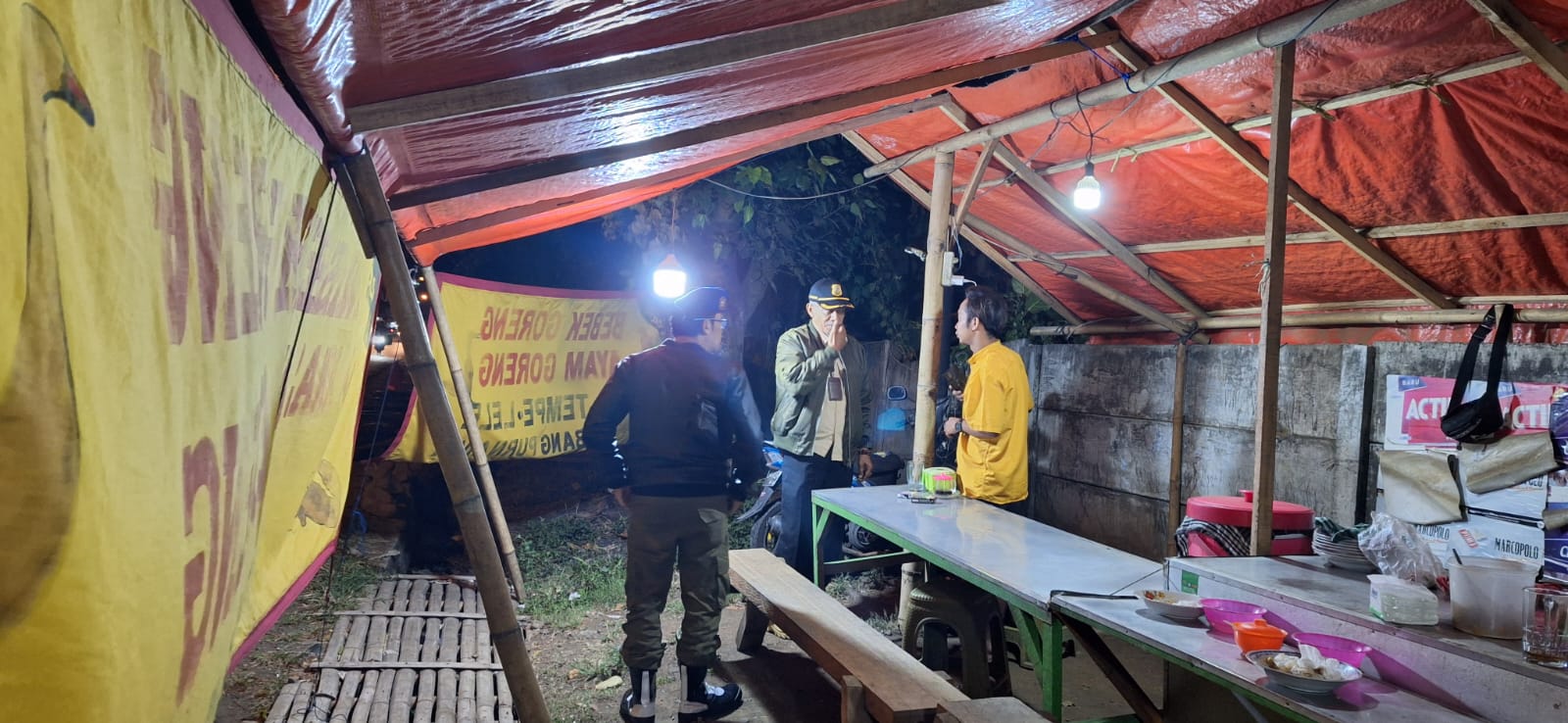 BURU PSK: Dua personel Satpol PP Kabupaten Malang berkomunikasi dengan pemilik salah satu warung di lokasi razia, Rabu malam (10/7).