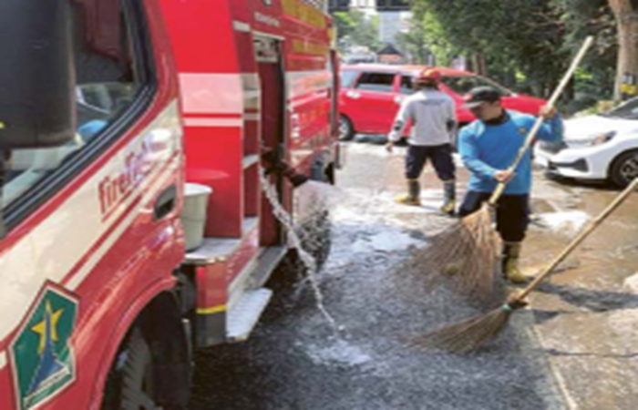 SEMPAT LICIN: Petugas Damkar Kota Malang membersihkan bekas tumpahan solar di Jalan Raya Balearjosari, kemarin.