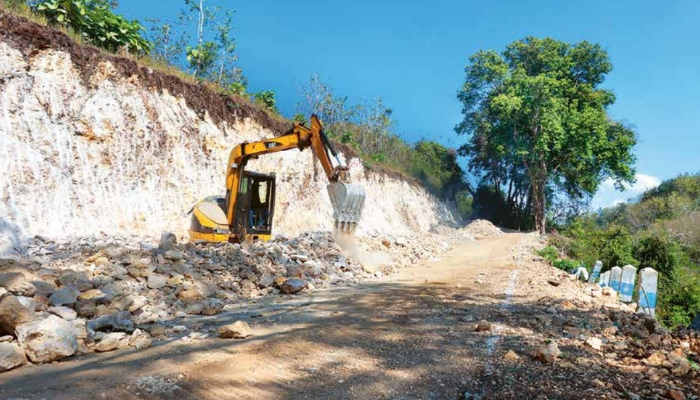 DILEBARKAN: Pekerja mengepras tebing di Jalan Rajekwesi, Desa Ngembul, Kecamatan Kalipare, Kabupaten Malang, menggunakan ekskavator kemarin (18/7).
