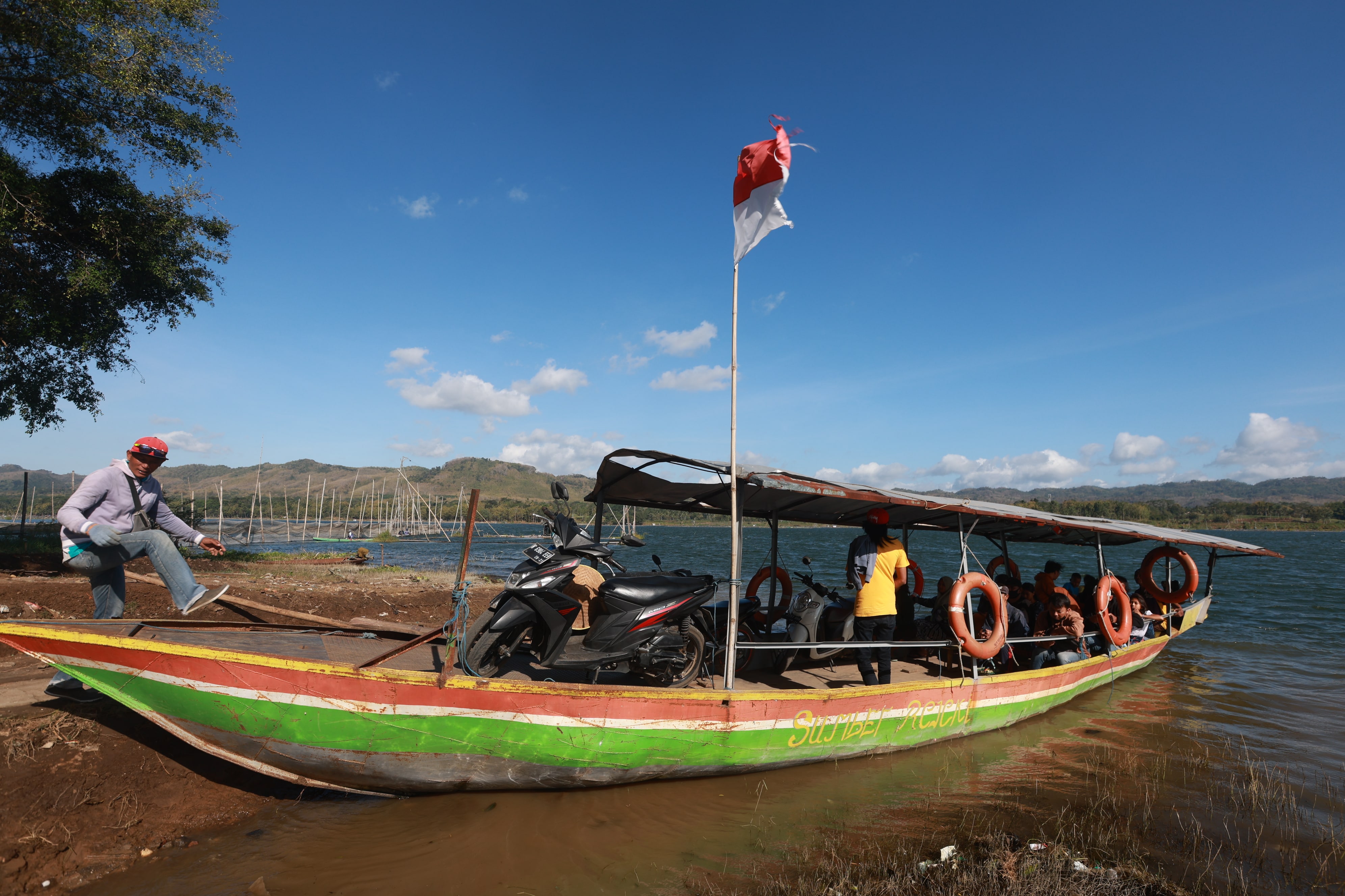 LINTAS KECAMATAN: Wandi mempersiapkan perahunya untuk mengantar penumpang yang ingin menyeberangi sungai kemarin (22/7).