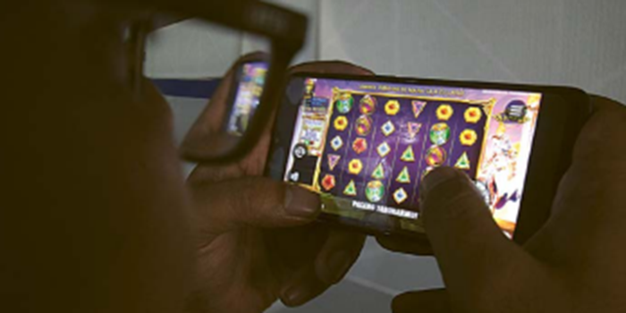 ASYIKNYA: Seorang pemuda bermain judi online (judol) di ponselnya. Polresta Malang Kota bakal gencar patroli keliling kota untuk membasmi judol.