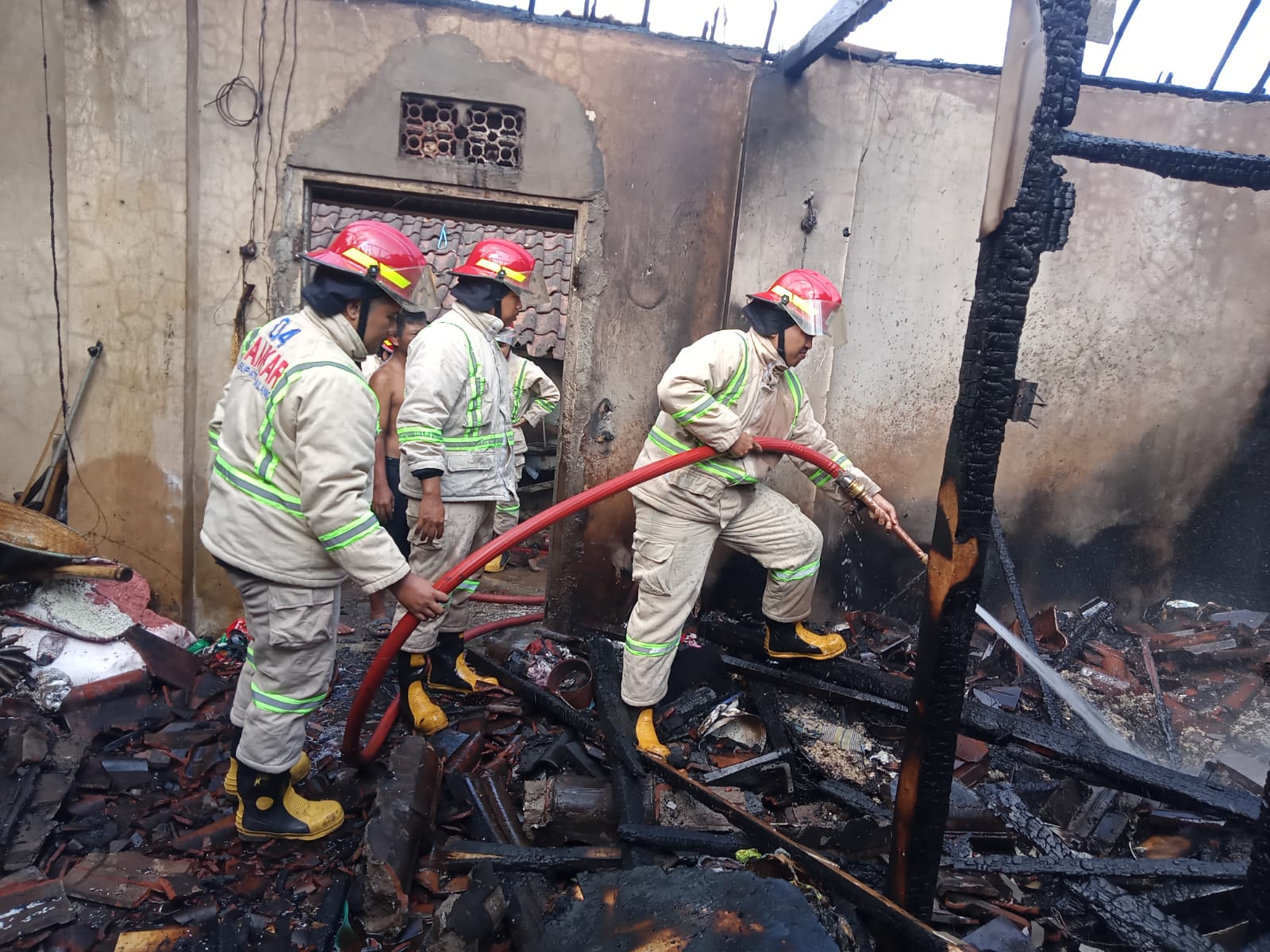 DIPICU KORSLETING: Para personel Damkar Kabupaten Malang memadamkan api sekaligus melakukan pendinginan kemarin (26/7).