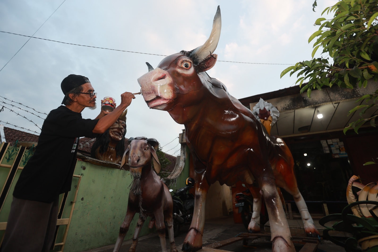 KREATIF: Supriatno, warga Desa Cempokomulyo, Kecamatan Kepanjen, mengerjakan patung sapi yang sudah tahap finishing.