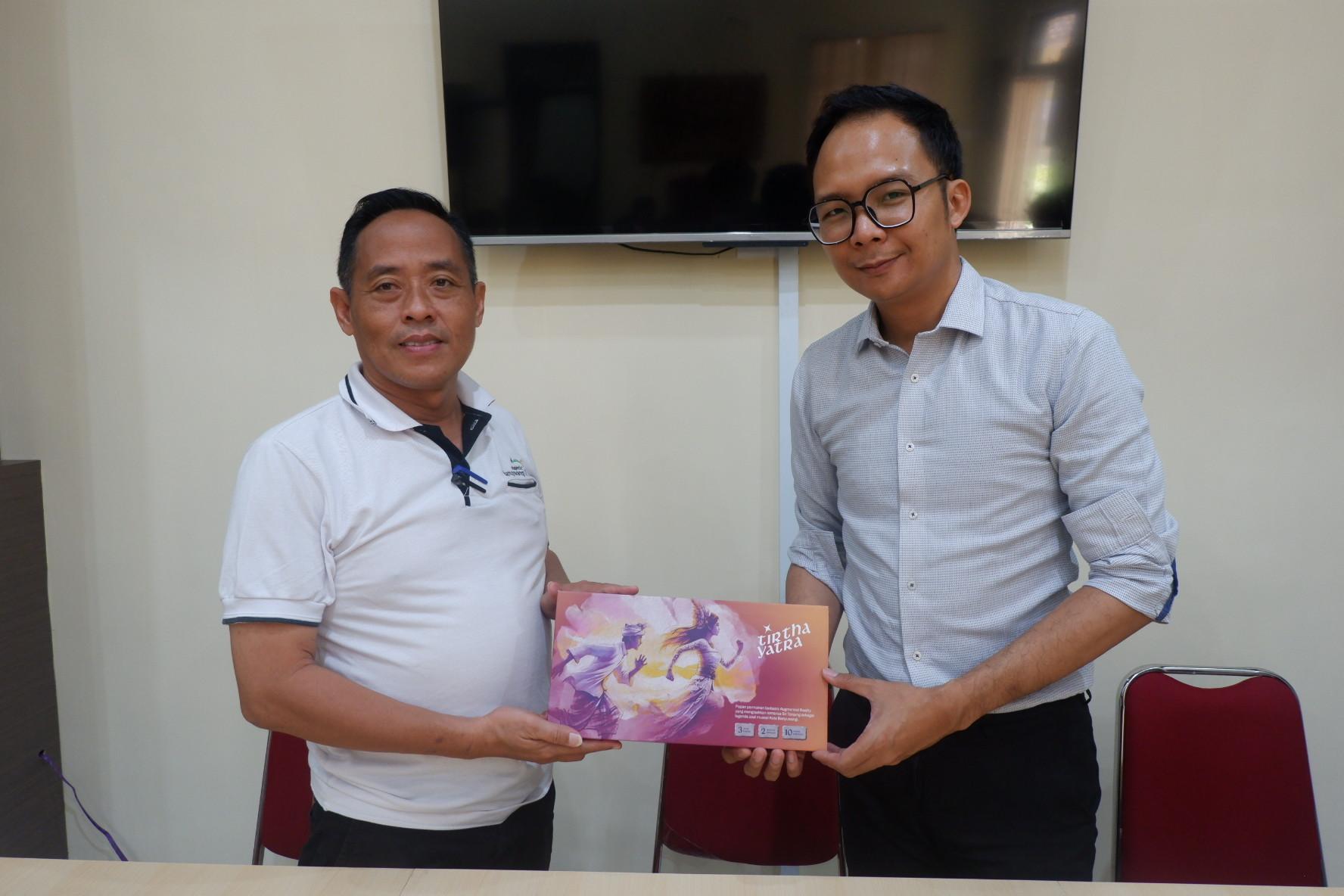CENDERAMATA: Ketua tim pengembangan Erlangga Setyawan (kanan) menyerahkan board game tirthayatra cenderamata ke Kepala Desa Benelanlor Khoirul Anam NLP