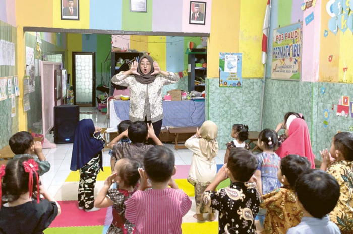 PENUH KECERIAAN: Seorang guru PAUD Permata Ibu di kawasan Gading Kasri, Klojen mengajak siswa menirukan gerakannya kemarin pagi.