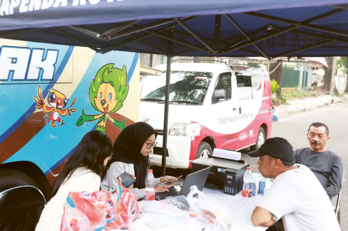 JEMPUT BOLA: Petugas Bapenda Kota Malang melayani warga yang hendak membayar pajak di CFD Ijen kemarin pagi.
