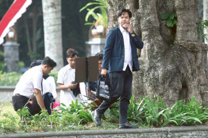 MENUJU PKKMB: Seorang mahasiswa Universitas Brawijaya (UB) berjalan di taman kampus dengan menggunakan jas almamater.