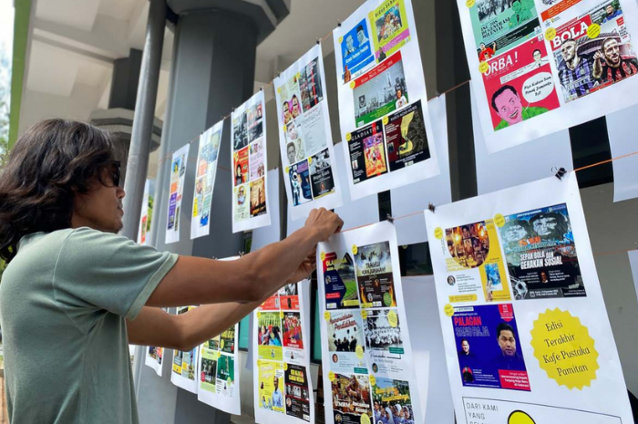 BANYAK KENANGAN: Salah satu pengunjung Kafe Pustaka memasang dokumentasi kegiatan yang pernah dilakukan di sana, kemarin.