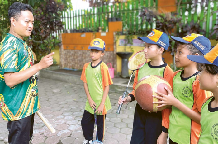 LATIHAN BERSAMA: Guru olahraga SDN Merjosari 5 menjelaskan cara bermain basket dan bulu tangkis pada Jumat (9/8).
