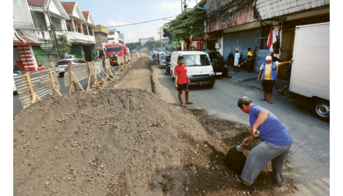 ANTISIPASI KECELAKAAN: Warga membersihkan material untuk pengurukan jalan yang meluber ke aspal di Jalan Laksamana Martadinata kemarin (13/8).