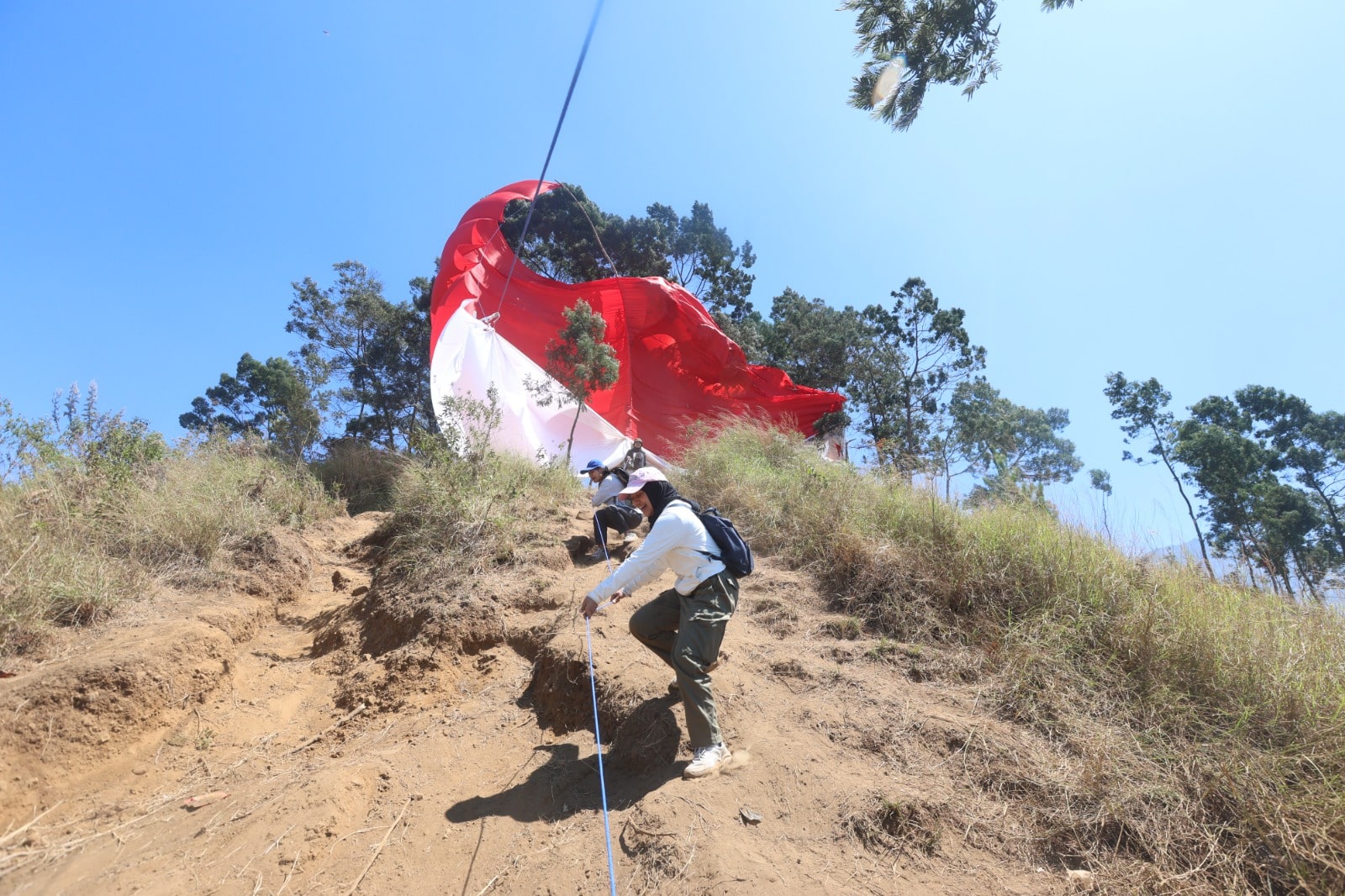 UDARA SEJUK: Wisatawan mengibarkan bendera merah putih di puncak bukit Budug Asu, Desa Toyomarto, Kecamatan Singosari, Kabupaten Malang, kemarin.