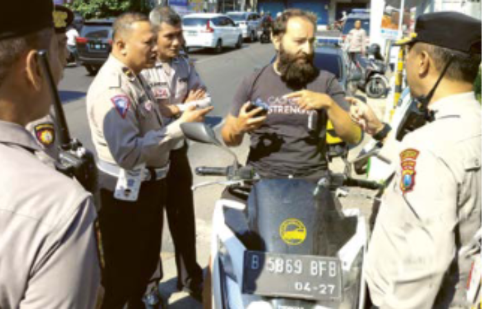 DIKIRA TAK BERTUAN: Anggota Polsek Lowokwaru memberi pengarahan kepada Vitaly Neborachok agar tidak memarkir motornya di trotoar Jembatan Tunggulmas kemarin (20/8).