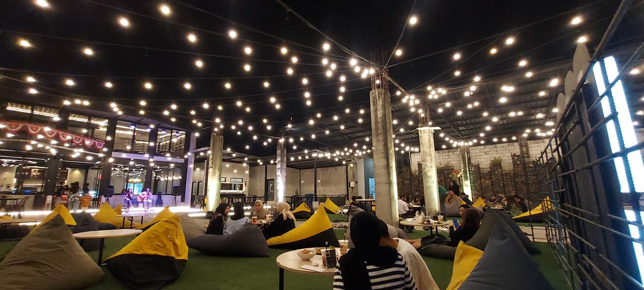 BERNUANSA ALAM: Pengunjung kafe Ko.Boy di Jalan Mayjen Panjaitan, Penanggungan, Kota Malang menikmati menu sambil bersantai di hamparan rumput sintetis