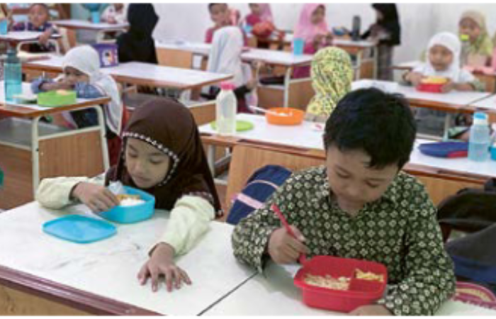 TUNGGU JUKNIS: Siswa kelas I SD Negeri Lowokwaru 5 makan bekal bersama, kemarin siang (22/8).