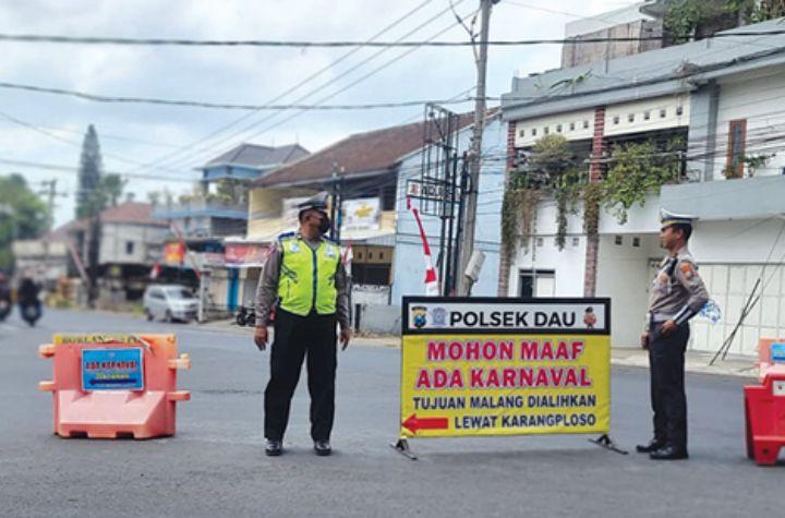 REKAYASA LALIN: Dua polisi berjaga di simpang tiga Pendem, Kota Batu, kemarin (26/8). Mereka mengarahkan kendaraan dari arah Kota Batu agar belok kiri menuju Karangploso.