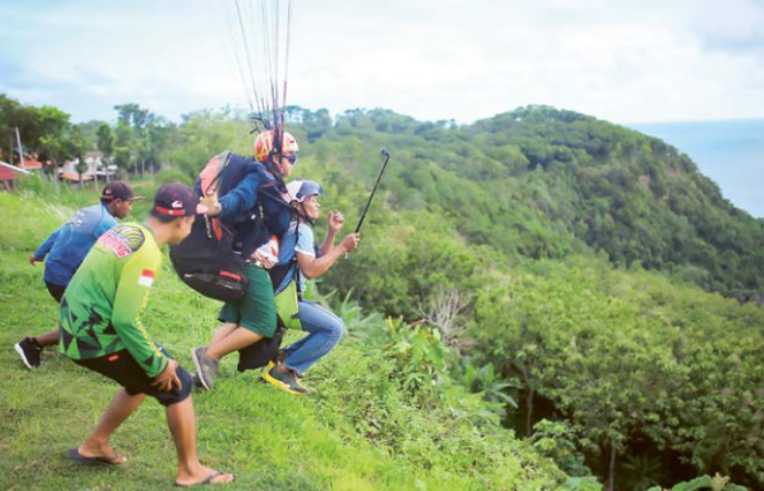 BAKAL DIKEMBANGKAN LAGI: Salah satu pengunjung menjajal tandem paralayang di Bukit Waung, Pantai Modangan, beberapa waktu lalu.