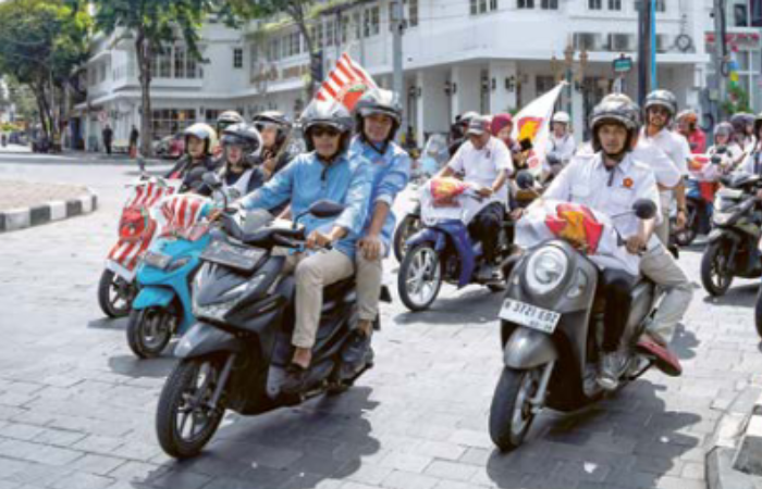 SATU KOMANDO: Wahyu Hidayat berboncengan dengan Ali Mu- thohirin dikawal para pendukung melintas di Jalan Basuki Rahmat.