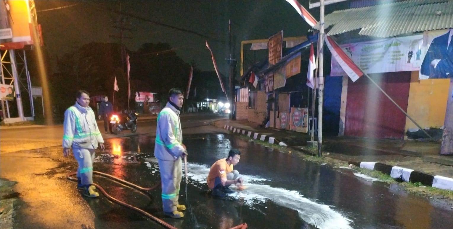 ANTISIPASI KECELAKAAN: Personel damkar Kabupaten Malang membersihkan tumpahan solar di depan SPBU menuju Bandara Abdul Rachman Saleh, Pakis.