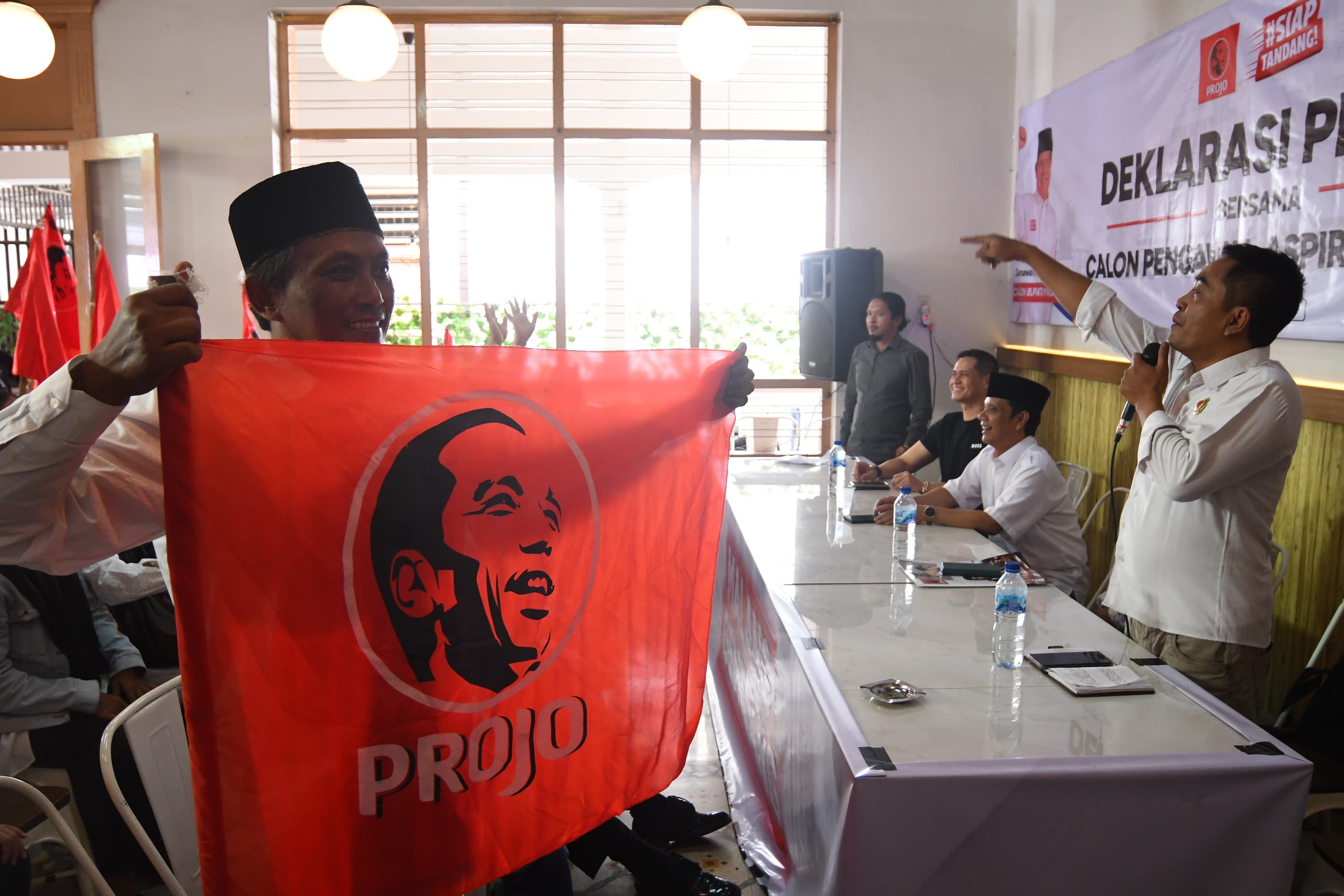 Seorang relawan membeber bendera projo bergambar presiden Jokowi