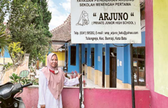 LENGANG: Kepala SMP Arjuno  Nurhayati berdiri di dekat papan nama  sekolah yang dibangun pada 1997 itu.