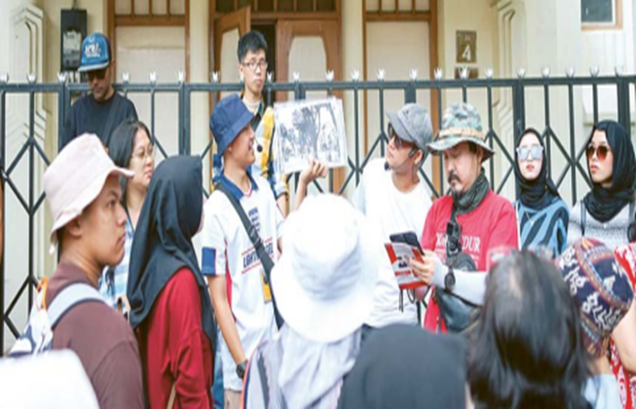PESERTA MENINGKAT: Salah satu pemandu menunjukkan foto lama Gedung Pertemuan Krida Sasana Budaya, Kelurahan Kiduldalem, Klojen, beberapa waktu lalu.