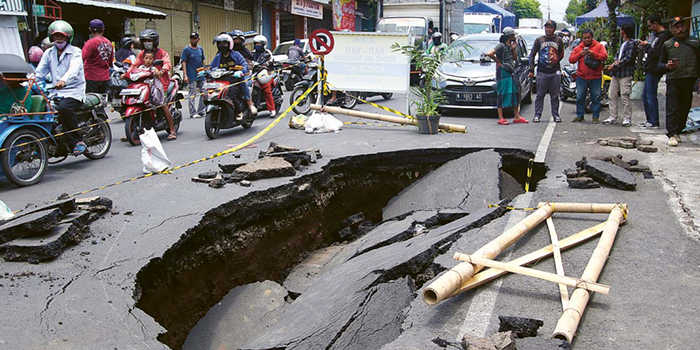DALAM PERBAIKAN: Sebagian badan Jalan Muharto ambles seluas 18 meter persegi akibat saluran air di bawahnya rapuh. Pemkot Malang berencana memasang box culvert di lokasi tersebut
