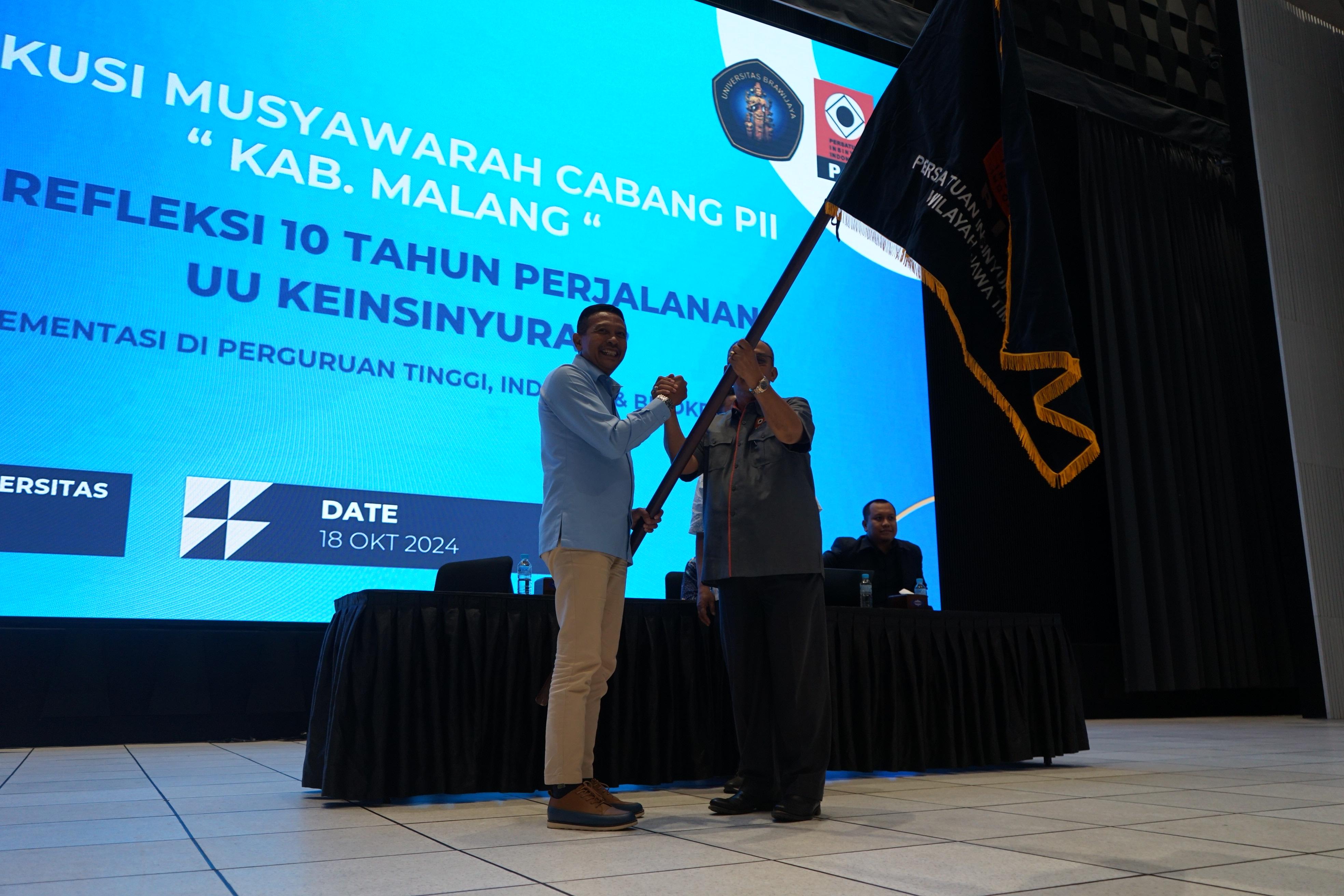SIMBOLIS: Ketua PC PII Kabupaten Malang Dr Ir Wahyu Hidayat MM (kiri) menerima bendera sebagai lambang mengemban tugas dan amanah.