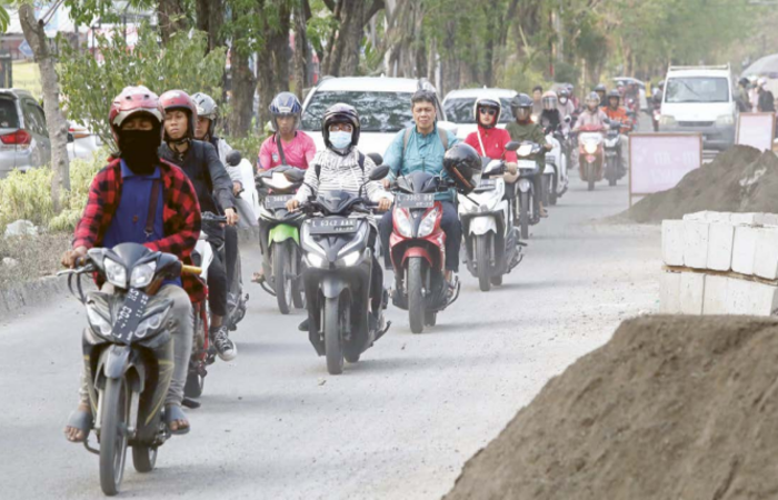 DIKELUHKAN: Pengendara sepeda motor melintas di Jalan Mulyosari kemarin. Karena berdebu, damkar harus menyiram jalanan sehari tiga kali.