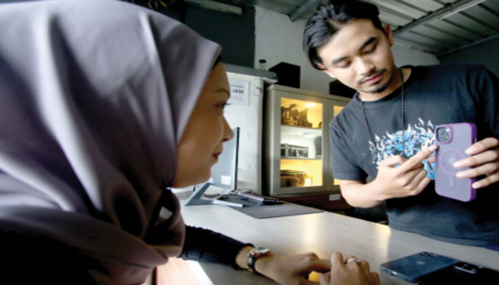 PEMINAT MENINGKAT: Petugas di Omah Visual di Jalan Terusan Kesatrian, Blimbing menunjukkan kondisi iPhone sebelum disewa customer.