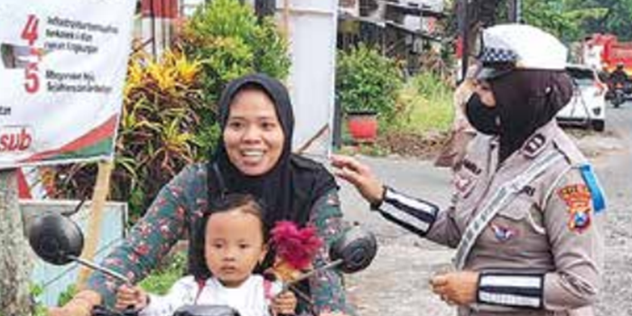 PERLU TAATI RAMBU LALIN: Polisi memberhentikan ibu-ibu yang berkendara di Jalan Raya Kepuharjo, Karangploso tidak menggunakan helm kemarin (27/10).