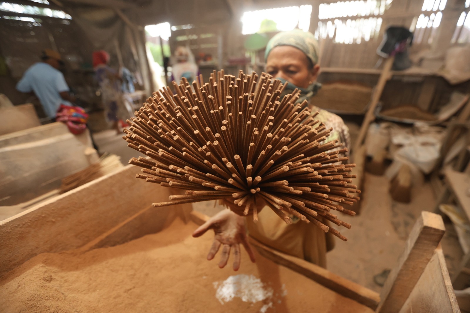 PRODUK LOKAL: Seorang pegawai home industry dupa di Desa Dalisodo, Kecamatan Wagir, Kabupaten Malang memegang stik kayu untuk dimasukkan ke wadah berisi serbuk kayu.