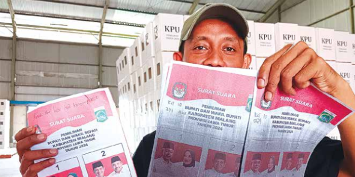 LOGISTIK: Salah seorang penyortir menunjukkan surat suara yang rusak di gudang KPU Kabupaten Malang, Desa Kebonagung, Pakisaji, kemarin (1/11).