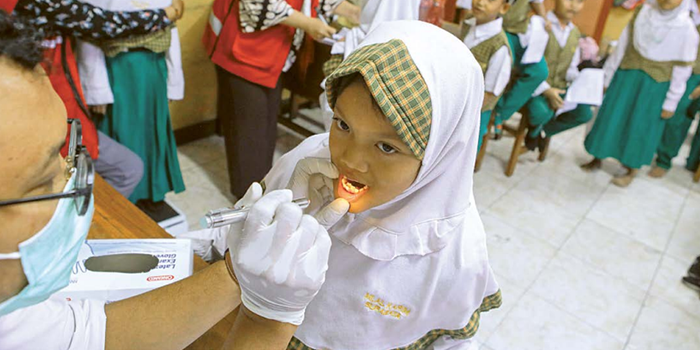 TETAP TENANG: Dokter dari Puskesmas Sidosermo memeriksa kondisi gigi siswa MI Al Karim kemarin pagi.
