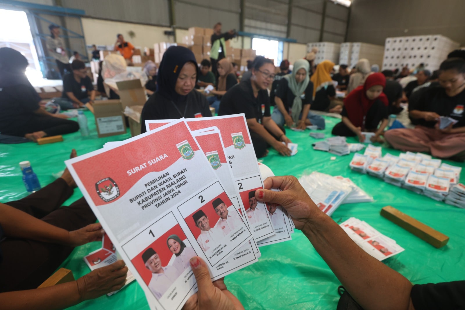 LOGISTIK PILKADA: Salah seorang tenaga sortir menunjukkan surat suara di gudang Komisi Pemilihan Umum (KPU) Kabupaten Malang. Lokasinya di Desa Kebonagung, Kecamatan Pakisaji.  &nbsp;