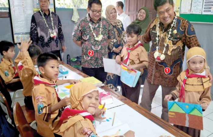 GENJOT LITERASI: 1) Kepala Disdikbud Kota Malang Suwarjana bersama 2) Direktur Jawa Pos Radar Malang Tauhid Wijaya menyapa sejumlah pelajar di SD Negeri Penanggungan, kemarin.