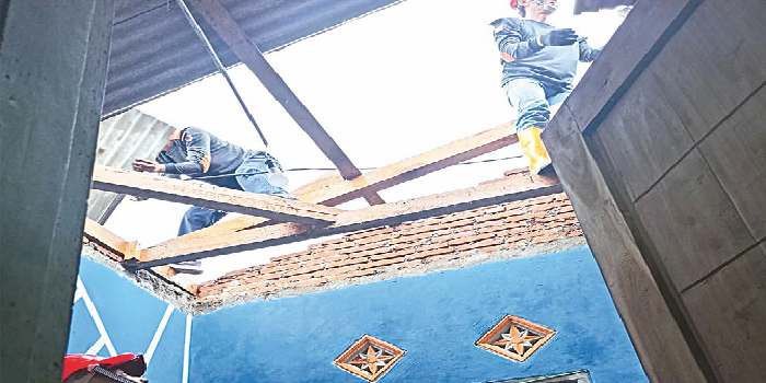 LANGSUNG DIPERBAIKI: Tim Destana Wonosari memperbaiki salah satu atap rumah warga yang jebol akibat hujan dan angin kencang kemarin. BPBD KABUPATEN MALANG FOR RADAR MALANG