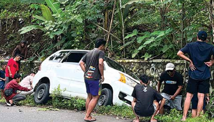 KECELAKAAN: Warga membantu mengevakuasi mobil Daihatsu Sigra berwarna putih yang terperosok selokan di Jalan Raya Argotirto, Desa Argotirto, Sumbermanjing Wetan, kemarin (1/12).