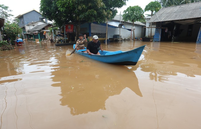 MASIH TERENDAM: Seorang warga Kampung Raas, Dusun Sendangbiru, Desa Tambakrejo, Kecamatan Sumbermanjing Wetan, membantu menyeberangkan tamu yang berkunjung ke kampung nelayan kemarin (1/12).