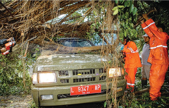 AKIBAT CUACA BURUK: Mobil patroli milik Satpol PP tertimpa pohon di persimpangan Jalan onggolawe dan Jalan Bintoro kemarin (10/12).