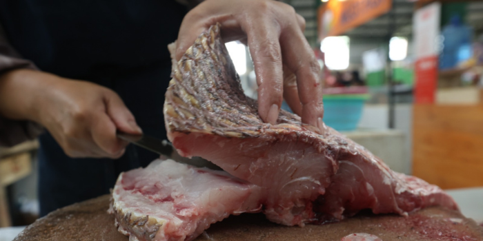 TERIMBAS CUACA: Salah satu pedagang di Pasar Klojen memotong ikan yang dibeli pelanggannya, kemarin.