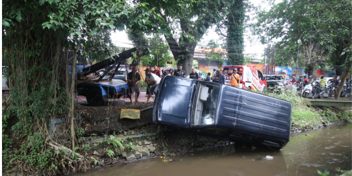 EVAKUASI: MobilI suzu Panther yang tercebur parit di Jalan Mayjen Sungkono, Kelurahan Buring, Kecamatan Kedungkandang, ditarik menggunakan mobil derek kemarin siang (16/12).