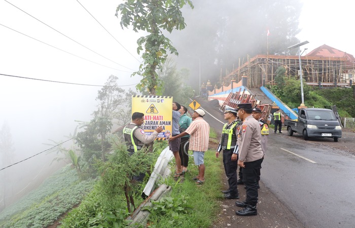 ANTISIPASI KECELAKAAN: Polisi bersama warga sekitar memasang banner berisi imbauan berhati-hati saat berkendara di jalur menuju wisata Bromo kemarin.