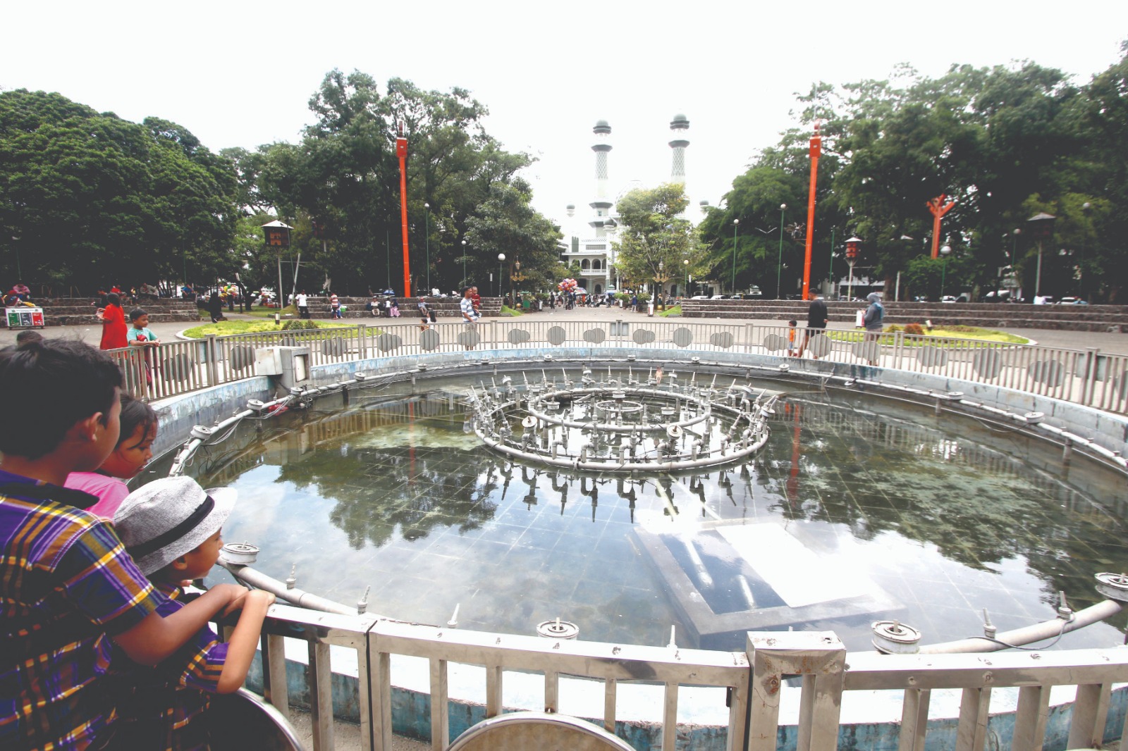 SEGERA DIKEBUT: Pengunjung melihat kolam yang berada di tengah Alun-Alun Merdeka kemarin siang. SATRIA CAHYONO / RADAR MALANG