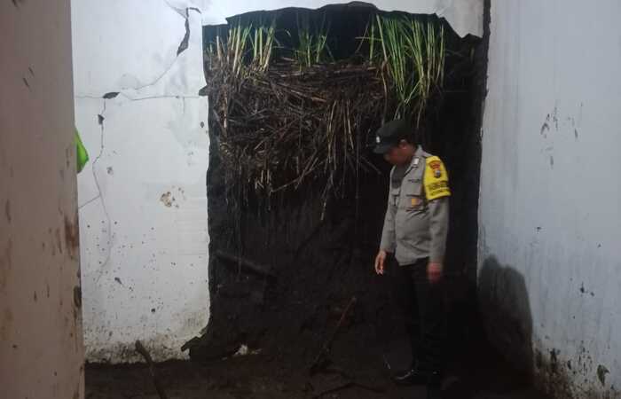 SALURKAN BANTUAN: Personel Polsek Pakis meninjau salah satu tembok rumah warga yang jebol, Selasa sore (24/12).