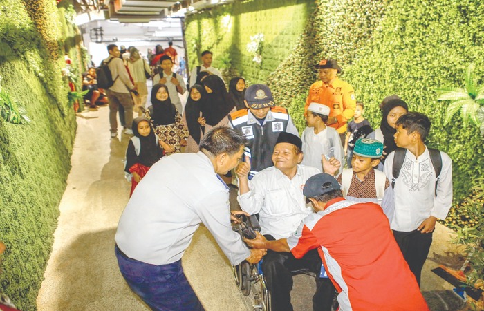 ANIMO TINGGI: Petugas membantu lansia yang melintas di terowongan Terminal Intermoda Joyoboyo (TIJ) menuju Kebun Binatang Surabaya (KBS) kemarin.